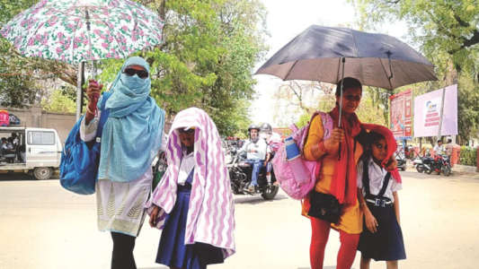 कानपुर की सड़कों पर चिलचिलाती धूप में छाता लेकर चलते लोग।