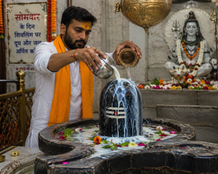 सोमवार के दिन शिवलिंग पर दूध और जल अर्पित करते हुए श्रद्धालु की तस्वीर